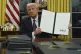 US President Donald Trump holds up an executive order commut