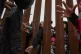 Migrants reach through a border wall for clothing handed out