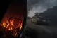 A Ukrainian tank passes by a burning car near the Russian-Uk