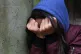 A teenage girl with her head in her hands showing signs of m