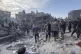 Palestinians stand and others search for survivors and bodie