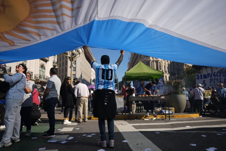 A laborer holds an Argentine flag during a May Day demonstration in Buenos Aires, Argentina, Thursday, April 30, 2026